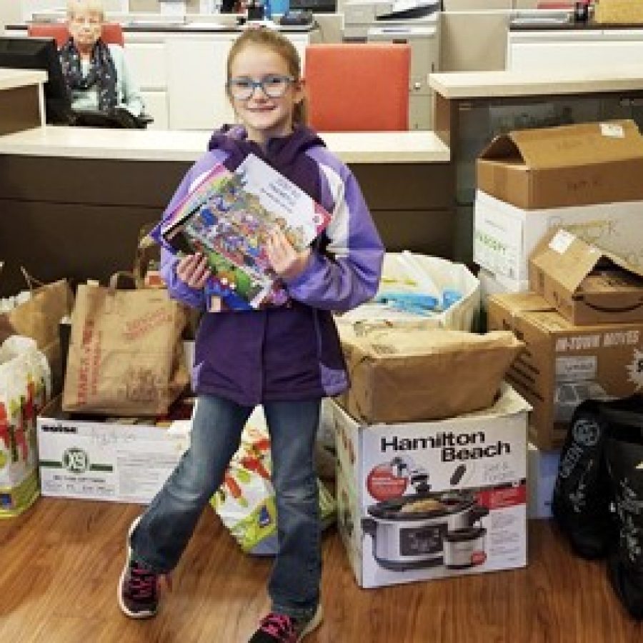 Long Elementary School second-grader Lily Yemm is pictured with the books she collected for the Ronald McDonald House at Mercy Hospital St. Louis.