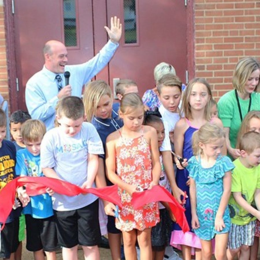 Mosaic Elementary Principal Scott Clark, hand raised, leads the students of the new school in chanting \We are Mosaic\ before they cut the ribbon of the new school Aug. 14.