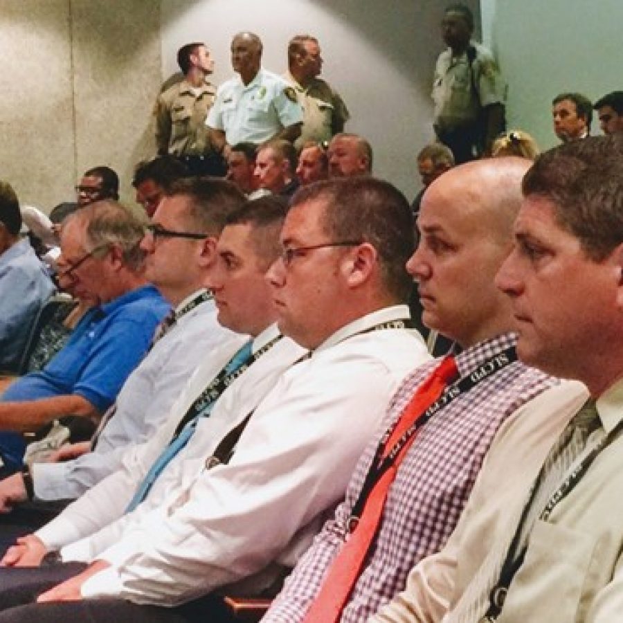 St. Louis County police officers, front, and Chief Jon Belmar, background, react to the County Councils vote to ask for an independent investigation into MetroLink officers allegedly slacking on the job.