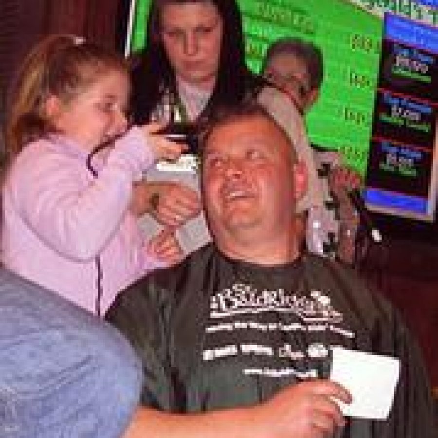 Challia Benae Reed shaves Capt. Kevin Reis head at the seventh annual St. Baldricks Foundation Event at Helen Fitzgeralds. 