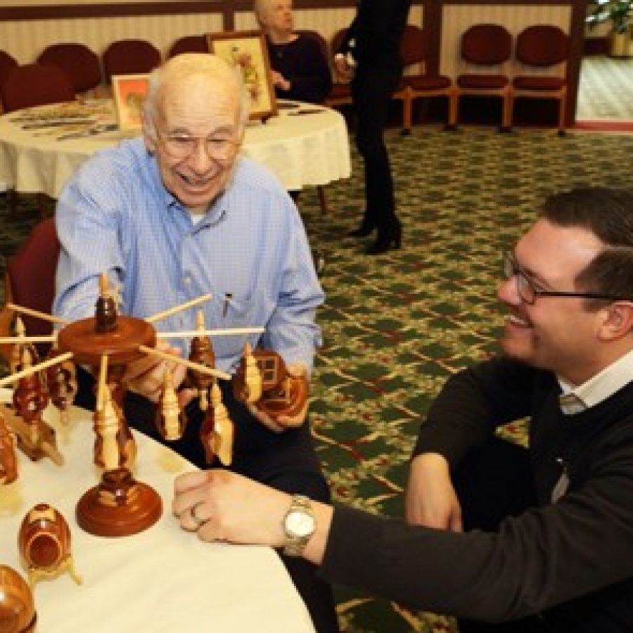 New Friendship Village Sunset Hills Executive Director Brian Cooper, right, inspects and discusses his woodworking art with Herb Bilgram at a community resident art show display.