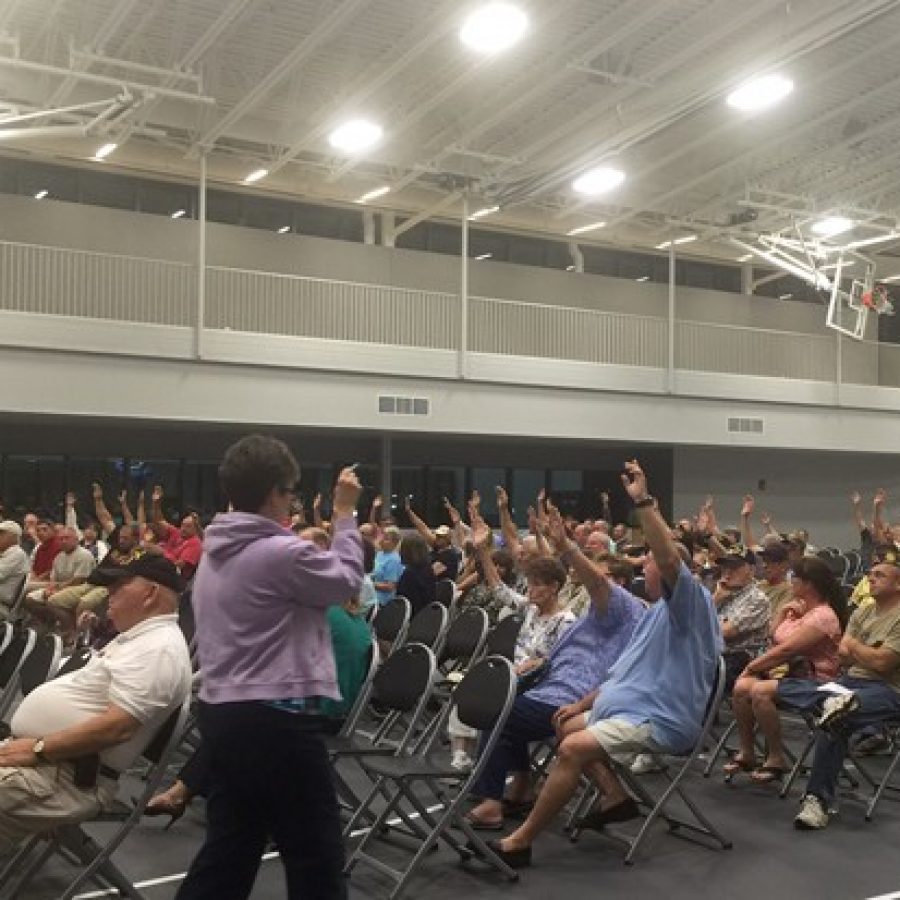 The crowd at one of the Sylvan Springs public hearings raises its hands in favor of selling the park to the Jefferson Barracks National Cemetery, as counted by county land-use manager Gail Choate.