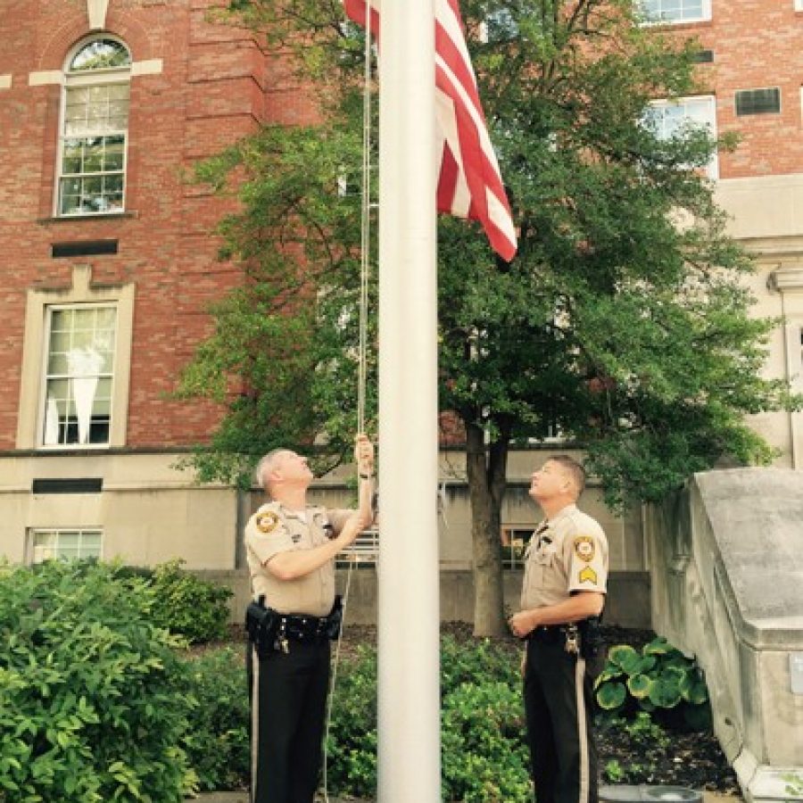 Sgt. Mike Castellano, left, and Sgt. Mike Stoehner lower the flag in front of the St. Louis County Police Department headquarters to half-staff in honor of Officer Blake Snyder, who was killed in the line of duty Thursday morning.