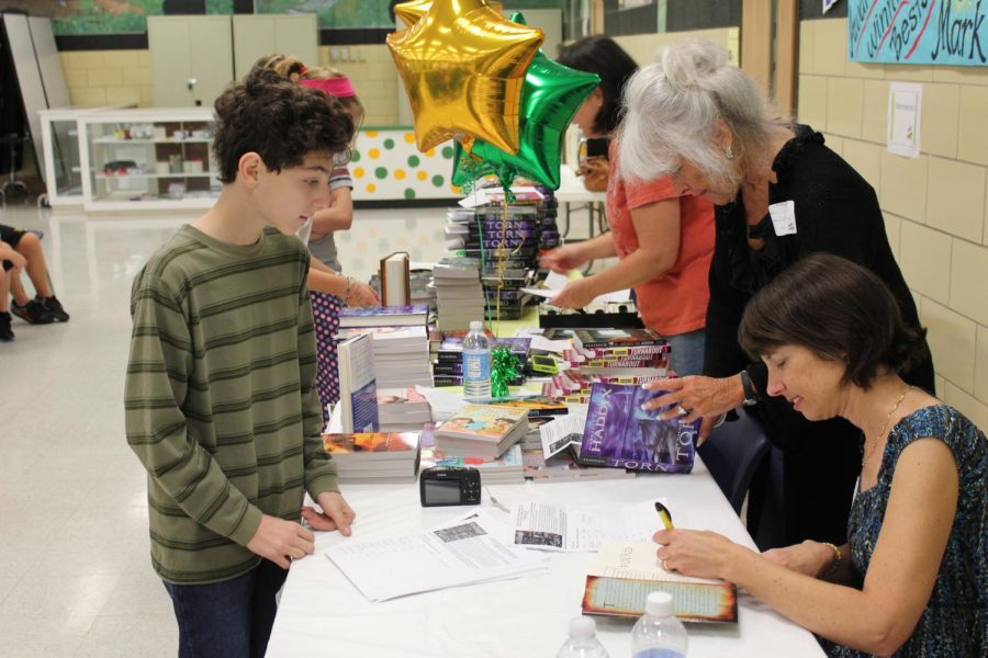 Award-winning author Margaret Peterson Haddix signs a book for Truman Middle School seventh-grader Nick Berra.