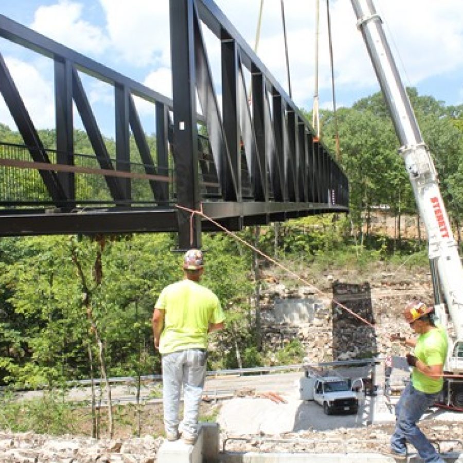 Workers lower one of the largest pedestrian trail bridges in St. Louis County into place at Cliff Cave Park in Oakville in July.