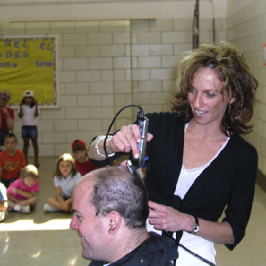 Stylist Shannon Rowan shaves the head of custodian Wayne Auer at Fridays all-school assembly at Blades Elementary School.