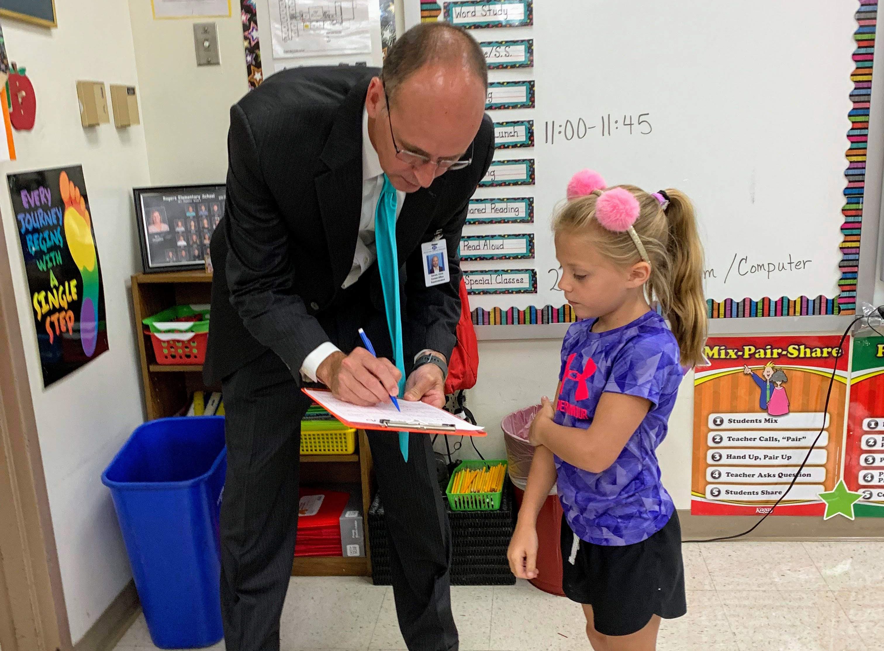 In the Rogers Elementary first-day-of-school scavenger hunt in 2019, second-grader Aleah Jacobsmeyer, right, and other students went straight to the top for help, asking Superintendent Chris Gaines if he fit any of their categories. He checked the box ‘I like vegetables.’ 
