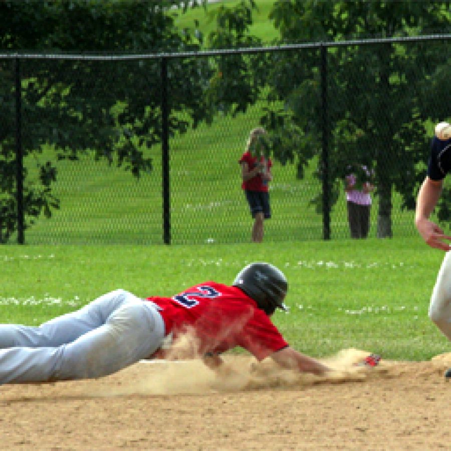 Oakvilles Alex Roedner slides head first toward first base to avoid being picked off in Sundays 15-12 loss to Maryland Heights.