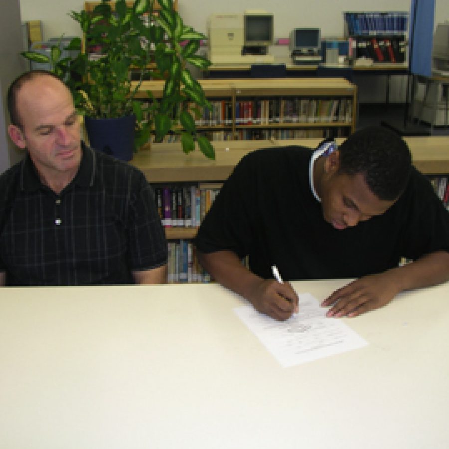 Randall Roberts, right, signs a letter of intent with Head Coach Gary Heyde looks on.