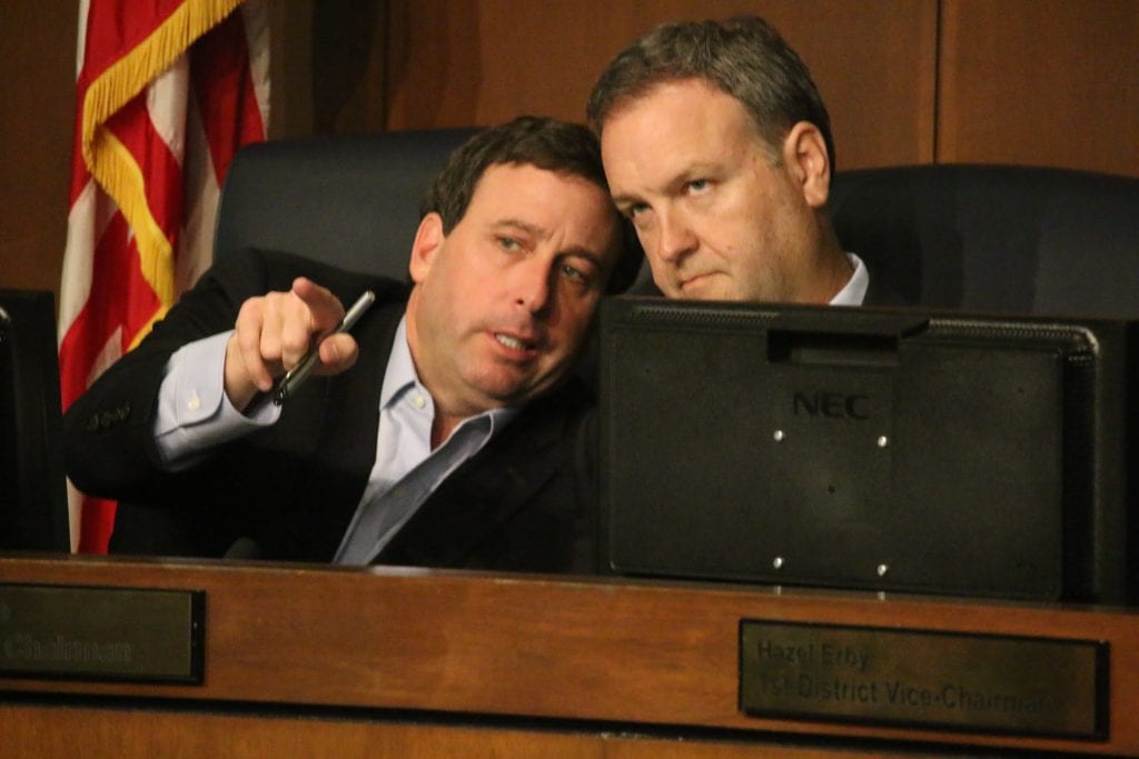 Former County Executive Steve Stenger, left, talks to then council Chairman Sam Page, D-Creve Coeur, at the Aug. 1 council meeting. Page became county executive April 19, after Stenger resigned from the position and pled guilty to federal corruption charges. Photo by Jessica Belle Kramer.