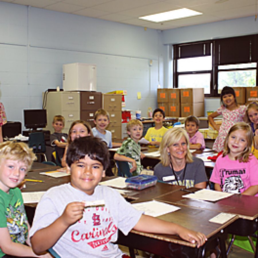 First-grade students in Nancy Boughmans class take a break from last day of school activities to smile for the camera. Their teachers moving boxes fill the room as Truman Elementary staff prepare to move out of the building this summer.