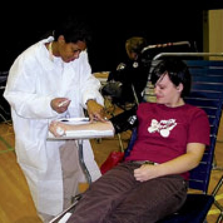 Red Cross phlebotomist Sunnie Thomas, left, assists Mehlville senior Sara Gaebler at the Student Council-sponsored blood drive. 