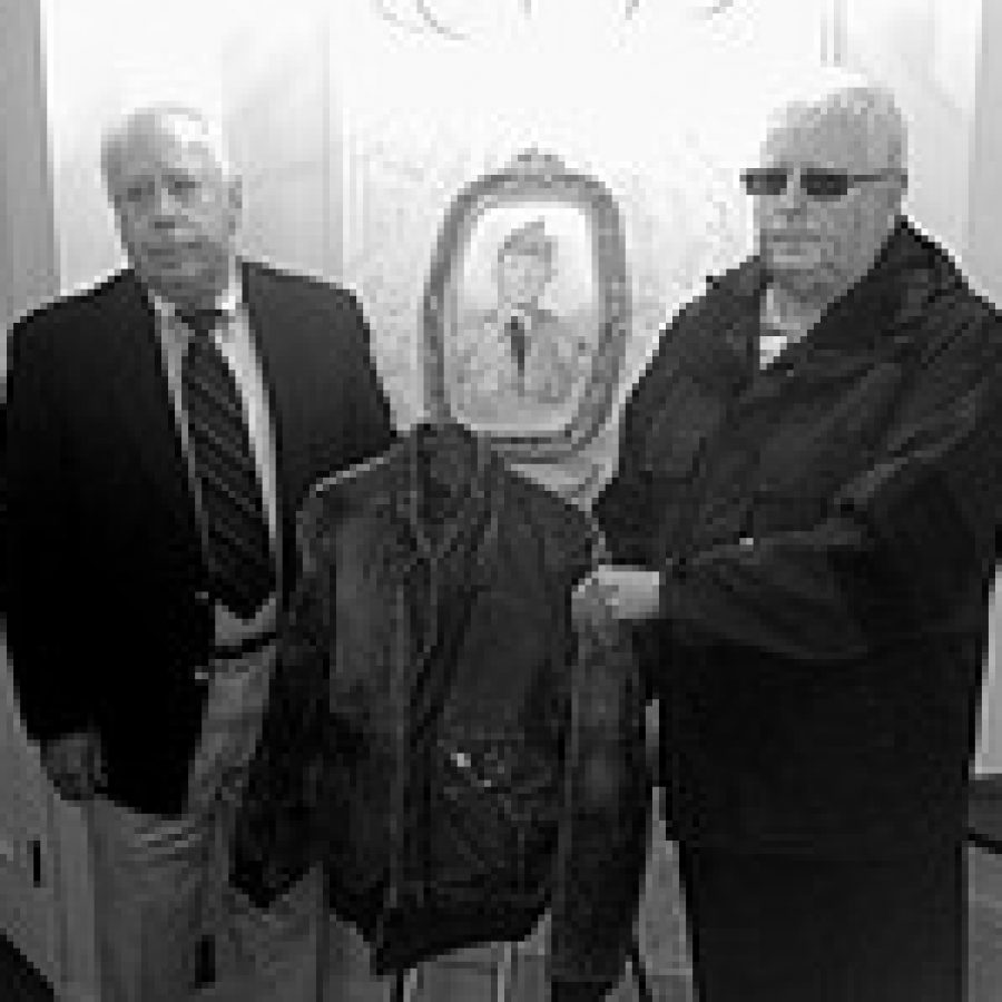 Brothers Gus and John Nelson hold a military jacket that belonged to their uncle, Cpl. James Larkin, Jr., who was killed in the Korean War in 1951. Larkins remains were returned to the U.S. in 2006 but were not positively identified until this year. A photo of Larkin in his uniform is in the background.  Photo by Lt. Col. Kevin McGhee 