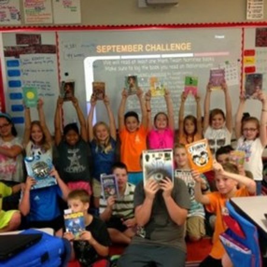 Students in Mallory Kruegers fifth-grade classroom at Sappington Elementary pose with their books, which need bookshelves, for Kruegers DonorsChoose request. 