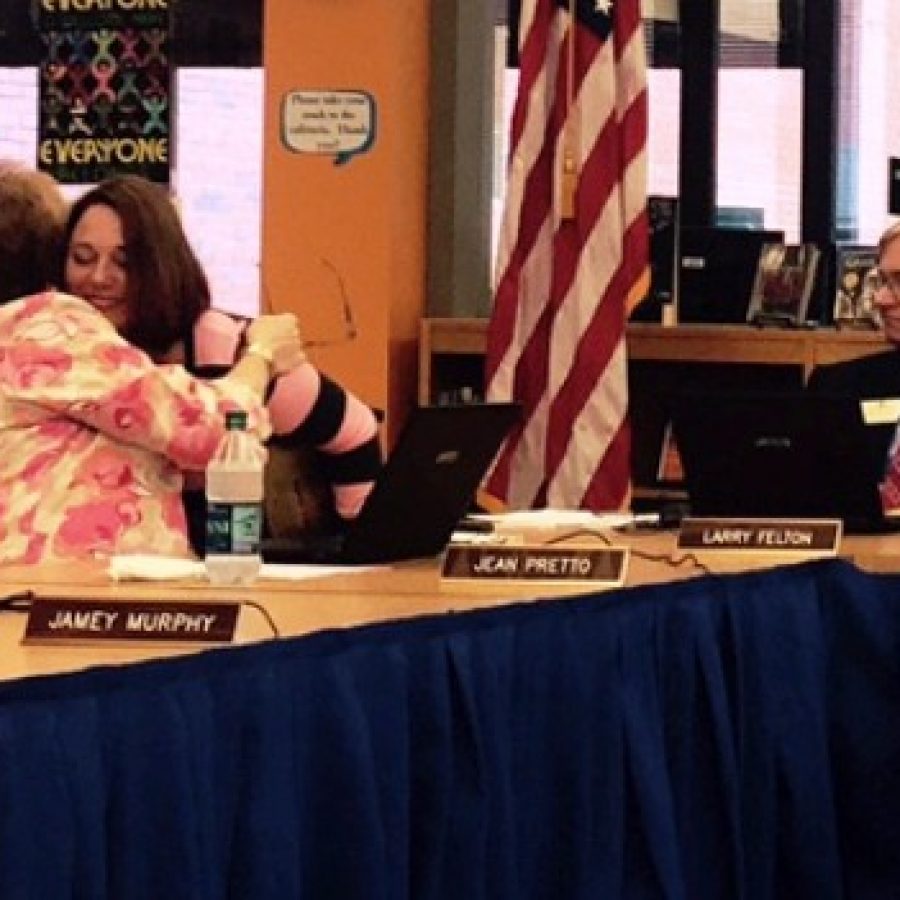 Board Vice President Jean Pretto, left, hugs exiting board member Lori Trakas as she leaves when her last meeting adjourned last week. Also pictured is board member Larry Felton.