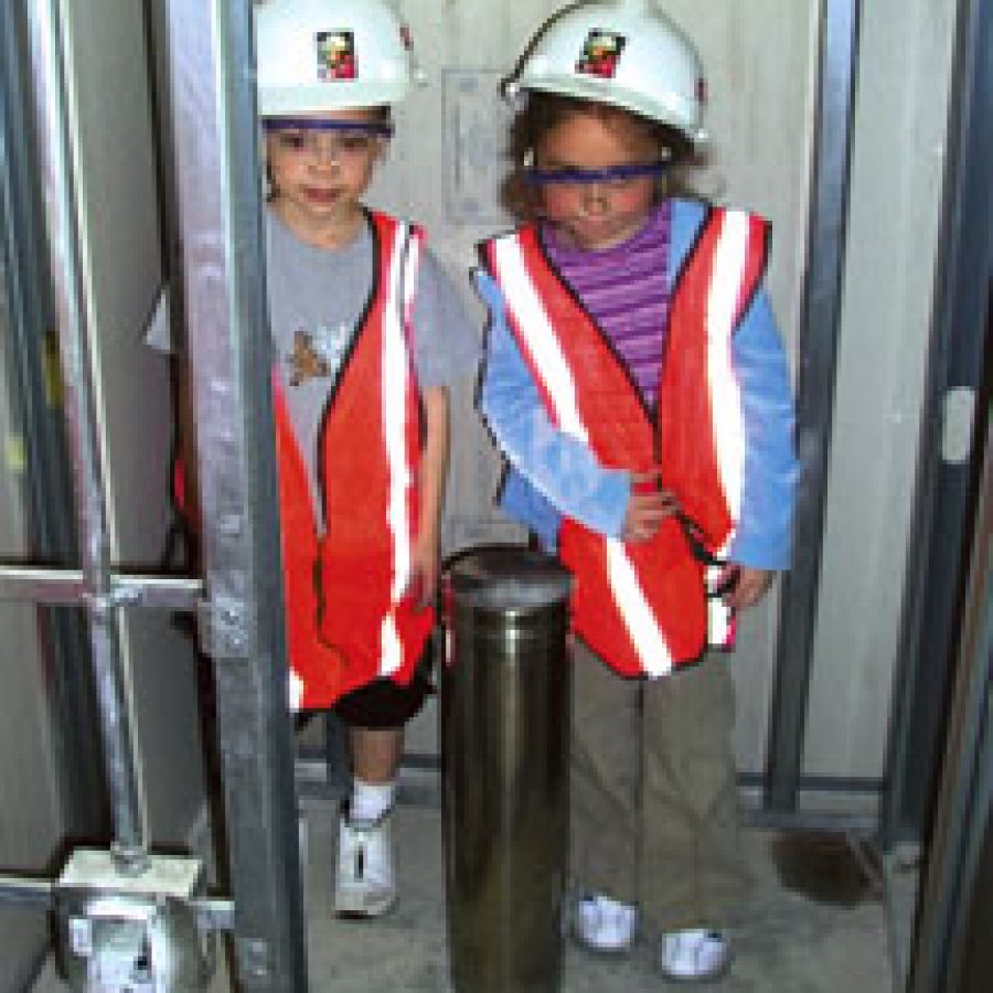 First-grade pupil Michael Schaeffer, left, and kindergartner Lauren Forbes position a time capsule, filled with messages and photos from 2004, at Oakville Elementary School — its resting place intended for at least 100 years. Pupils then watched as construction workers buried the stainless-steel capsule by putting up drywall at the new school, which is scheduled to open its doors this September.
