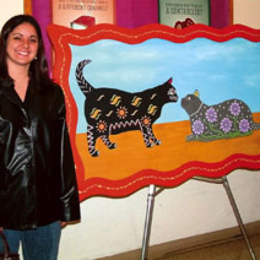 Oakville Elementary art teacher Lia Sova poses for a photo next to the large acrylic painting of her cats, which is on display at the We Love Our Pets exhibit.