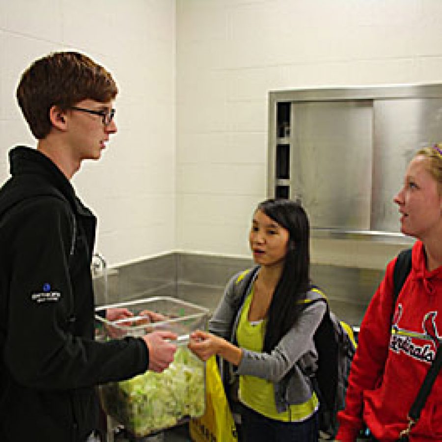 Seniors Drew Wetherington, Maria Nguyen and Katelyn Freund collect lettuce and other vegetables in the Lindbergh High School cafeteria. The students take the disposed-of food to a compost bin outside near the baseball fields.
