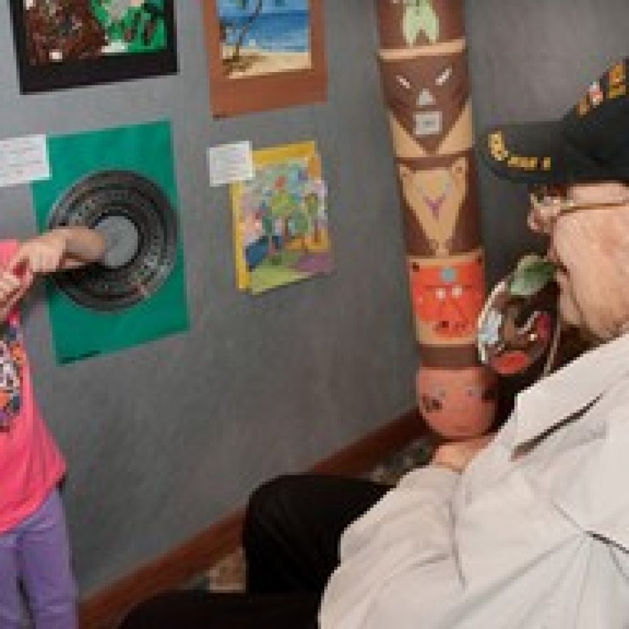 Mikayla Kaylie Casey, a 6-year-old Holy Cross student, shows off her art work to the delight of Gordon E. Gregory, 86, resident at Fountain View Assisted Living, Friendship Village Sunset Hills. Kaylie, a kindergarten student, helped earn Holy Cross Academy, Crestwood, second place and \$500 in the community's Young at Art Show.  