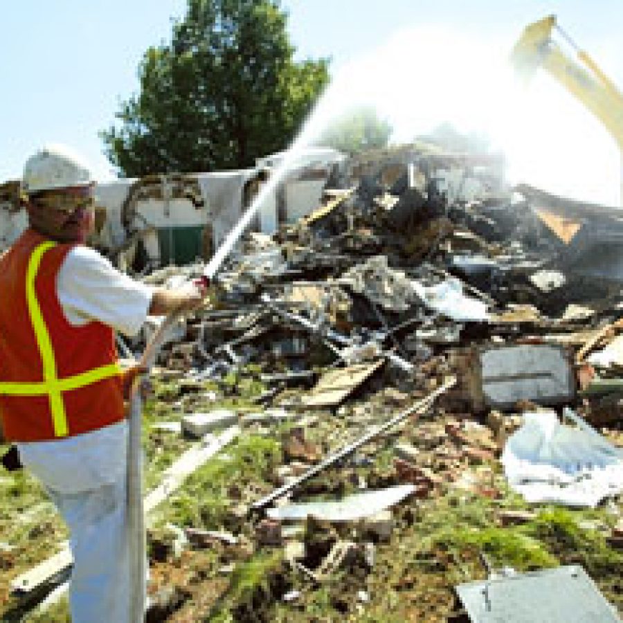 Mike Kent of Premier Demolition Inc. in Cedar Hill keeps a spray of water on debris from the demolition of the old Bernard Elementary School on Forder Road. Kent said last week that the spray helps keep dust from mi-grating to neighboring homes from the demolition site.
Bill Milligan photo
 