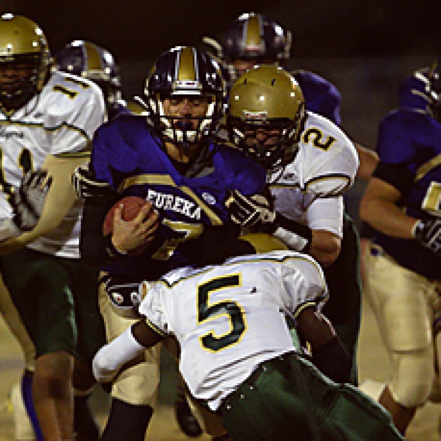 Eureka quarterback Sean Strehl grimaces as hes caught between hits by Lindberghs Tim Hamm-Bey, 5, and Matt Klingler, 2, on this short gain Friday night. The Wildcats lost Strehl after this play as the Flyers went on to win 14-6. Bill Milligan photo