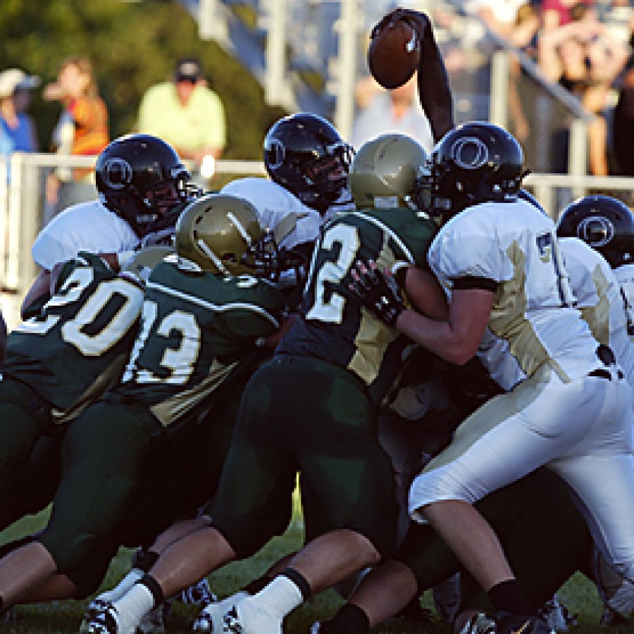 His forward progress nearly halted by a wall of players from both teams, Oakville High School quarterback Javon Henderson attempts to pierce the goal plane by reaching out over the crowd with the football during a successful Lindbergh first-quarter goal line stand Friday night. The Flyers prevailed 39-7. Bill Milligan photo