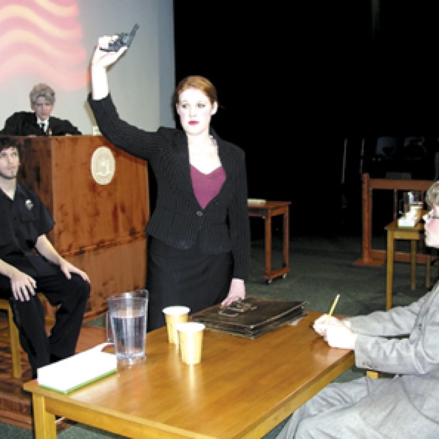 Prosecuting attorney Flint Kate Barton surprises the courtroom by revealing the murder weapon during Officer Sweeneys Jake Adams testimony in a scene from the Mehlville High School play The Night of January 16. Also pictured are Judge Heath Travis Brinker and Flints assistant Zach Barton.