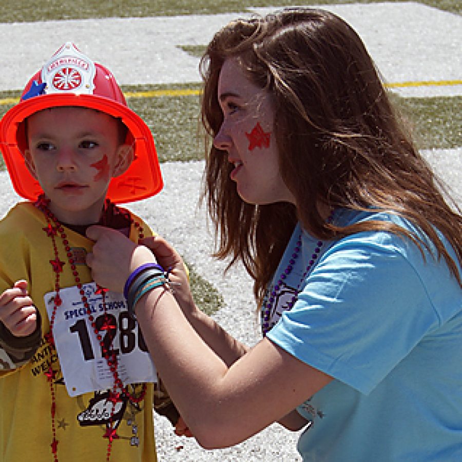 Mehlville High freshman Kaitlyn Krejci pins a ribbon on the shirt of her buddy, Point Elementary kindergartner Dallas Wallace, at MHS 14th annual Special Olympics held on May 4 at Jack Jordan Stadium on the MHS campus.