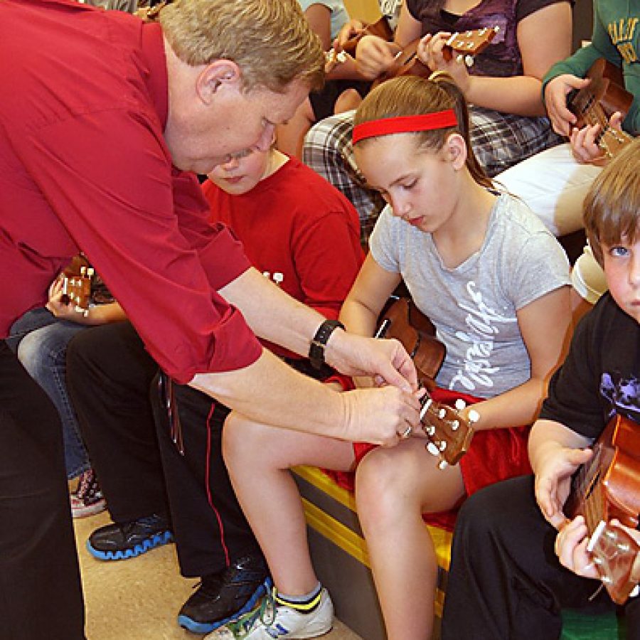 Fred Willman helps Oakville Elementary School fifth-grader Madyson McQuilling during the ukulele workshop he presented at no cost for the schools fifth-graders.