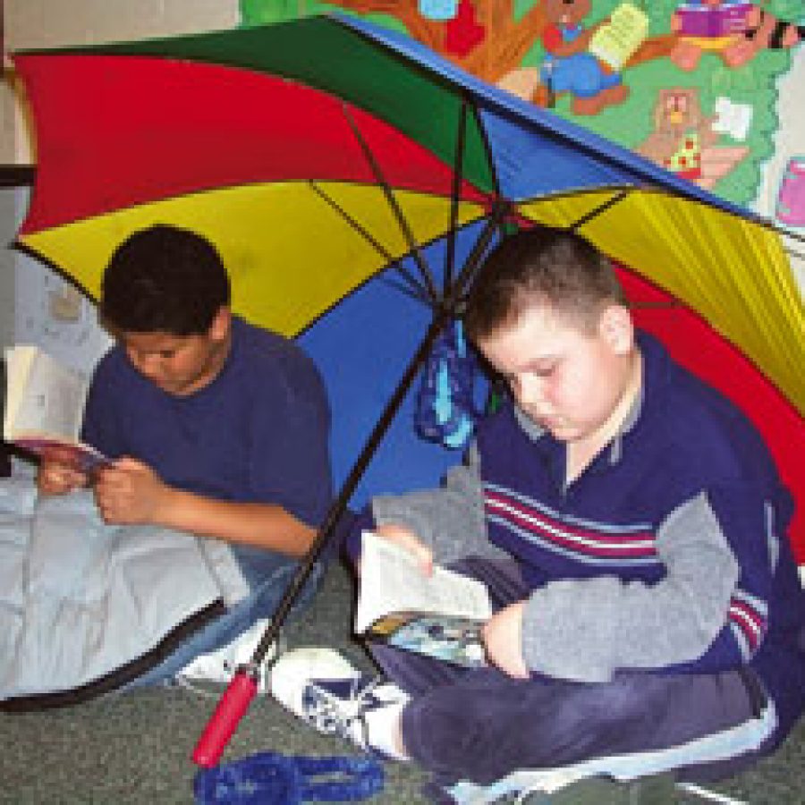 During Forder Elementary Schools Reading Day at the Beach, fourth-grade pupils Avion Mancel, left, and Mirsad Dzindic read their favorite books under a beach umbrella.
